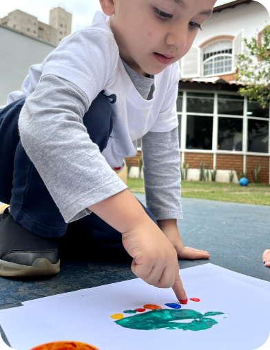Criança pintando com o dedo no papel