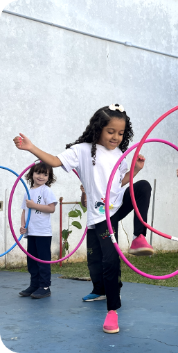 Crianças brincando de bambolê no pátio
