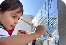 Criança pintando um painel com pincel